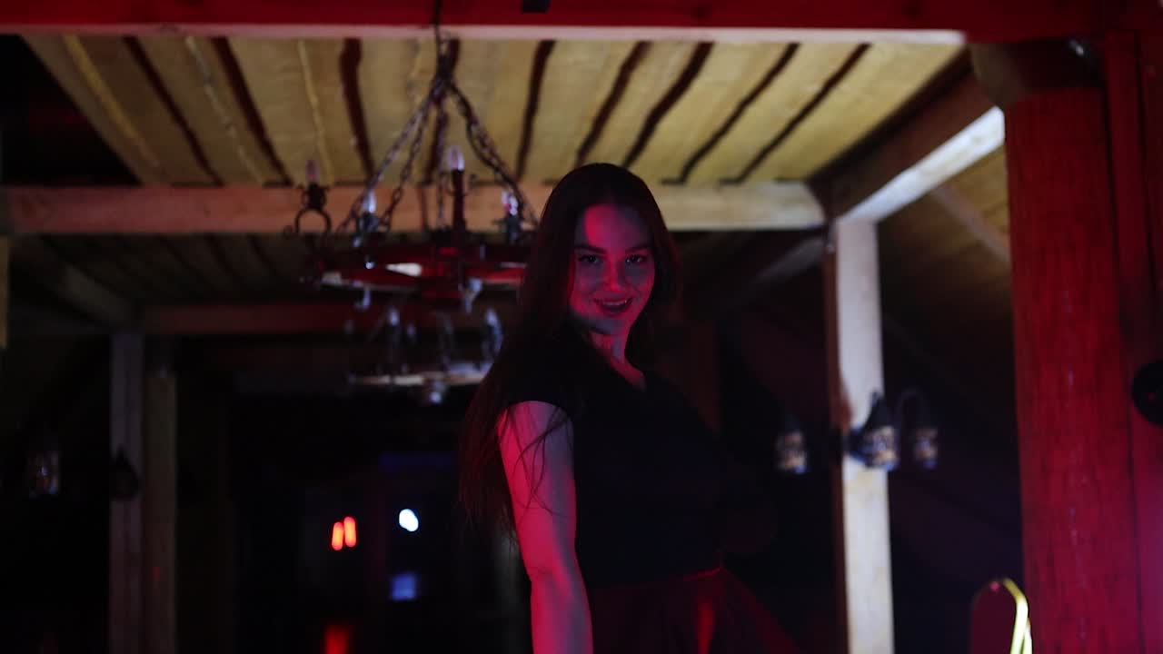 Giovane ballerina affascinante e piena di energia che si esibisce in un ambiente rosso scuro