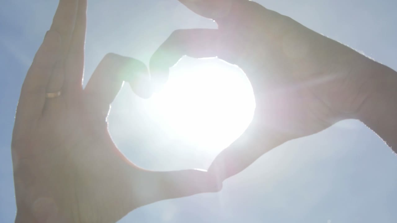Hands forming a heart shape around the sun