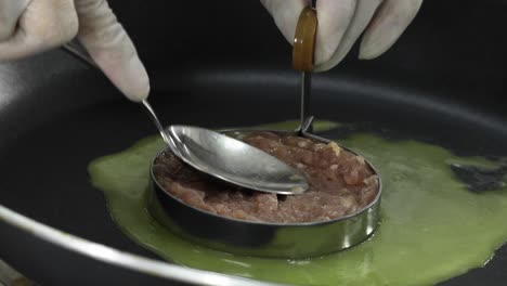 poner a mano la carne de cerdo cruda en el molde en la estufa de gas caliente con mantequilla derretida para sabor y buen olor preparar ingredientes para hacer hamburguesas caseras.