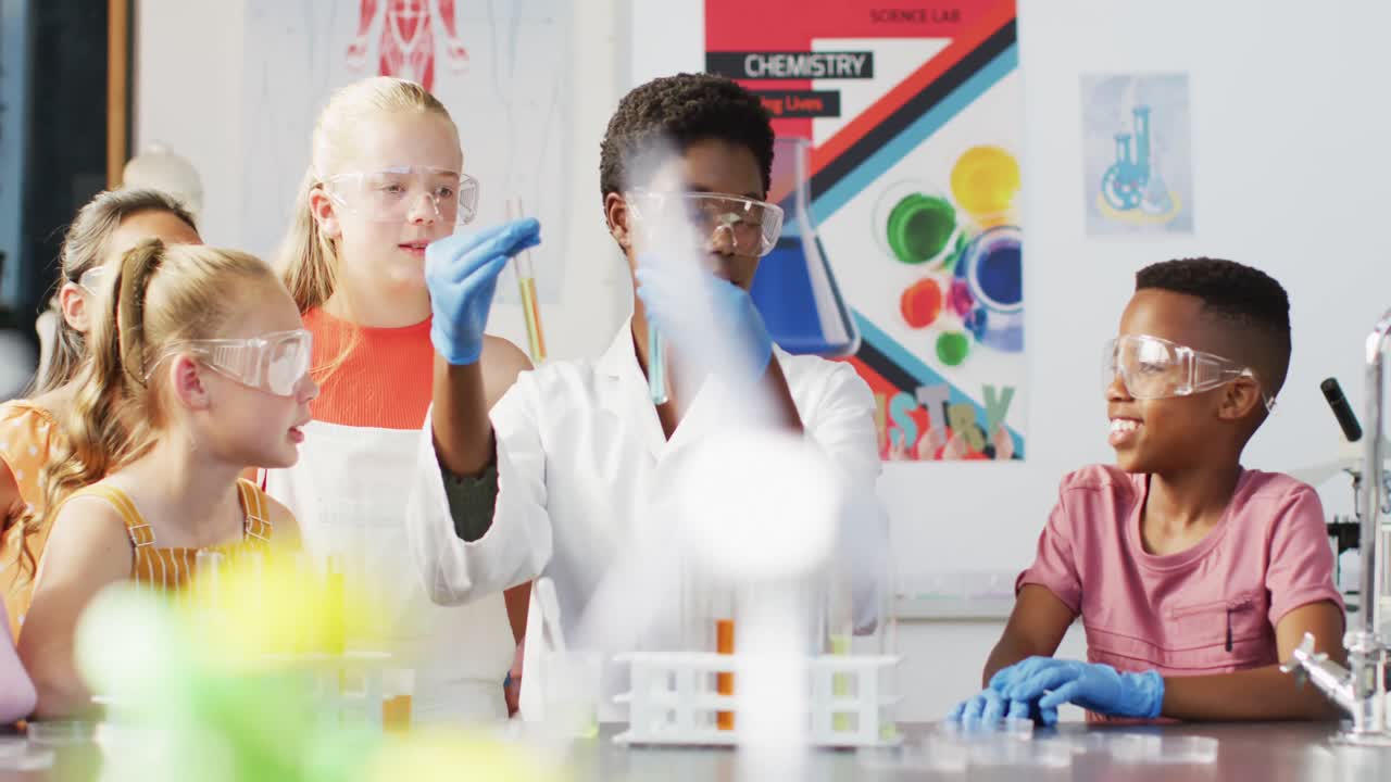 maestra diversa y escolares felices teniendo clase de ciencias en el laboratorio escolar