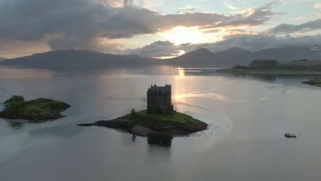 an aerial view of castle stalker on loch laich as the sun begins to set