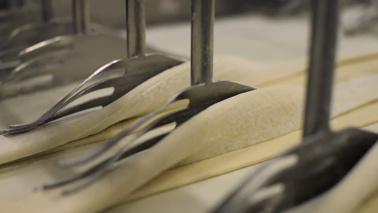 folding raw pastry dough automatically by industrial automated machine inside a bread factory