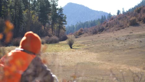 Hunter-waits-in-field-with-mountain-in-background