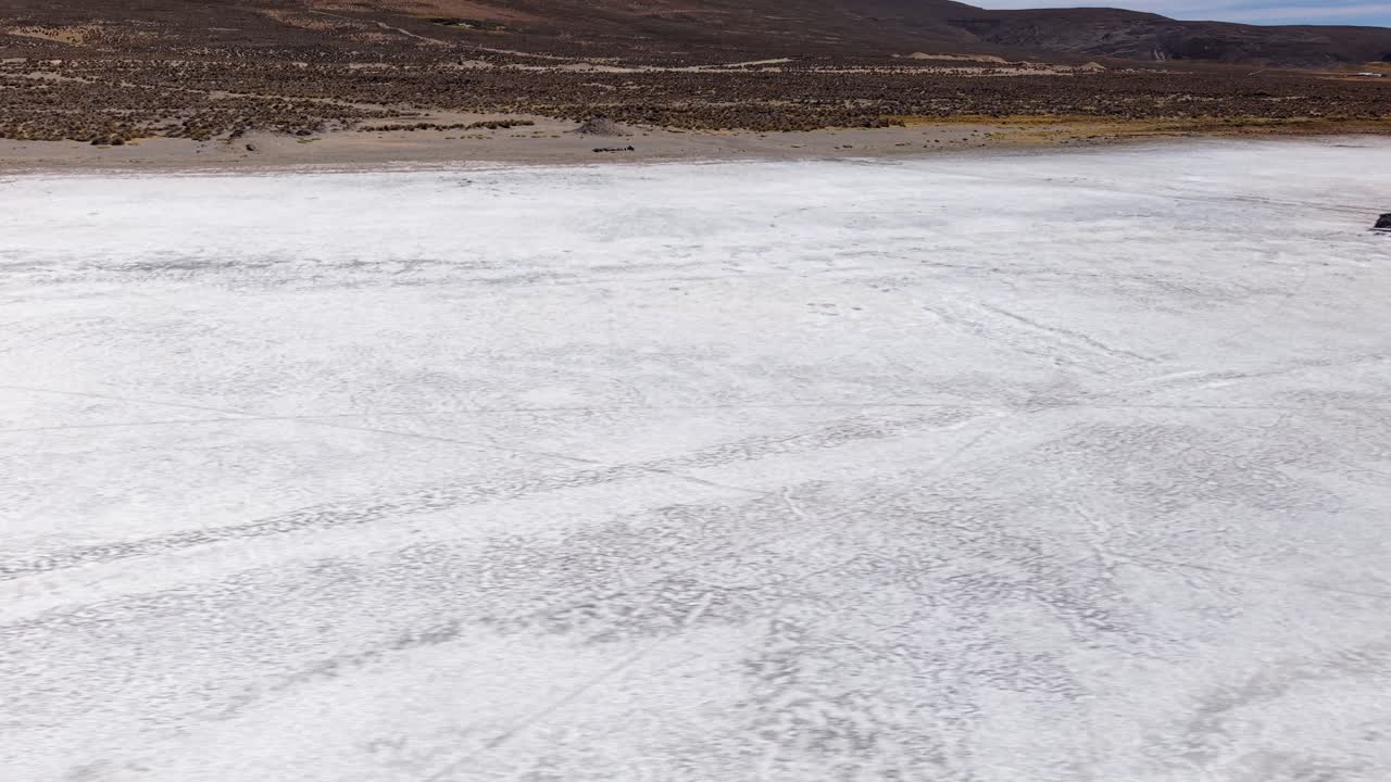 Low drone panning shot across the salt surface of Laguna de Salinas in Peru