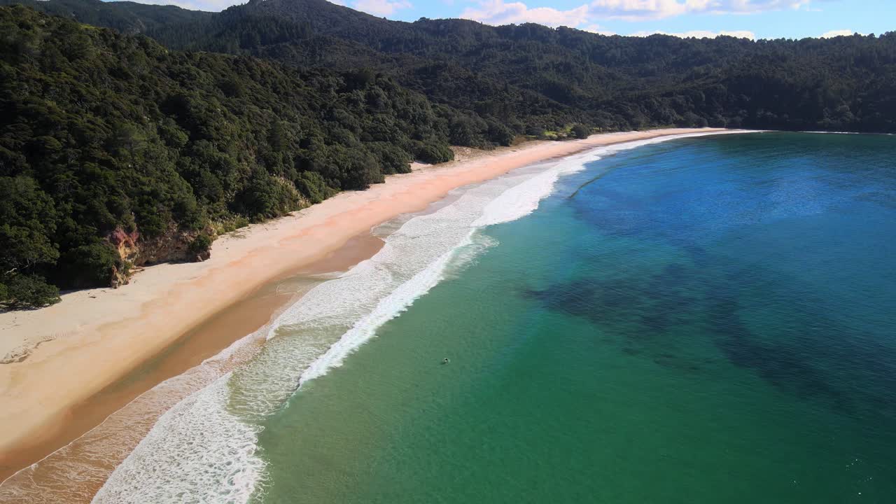 surfeando la playa new chums en coromandel de nueva zelanda