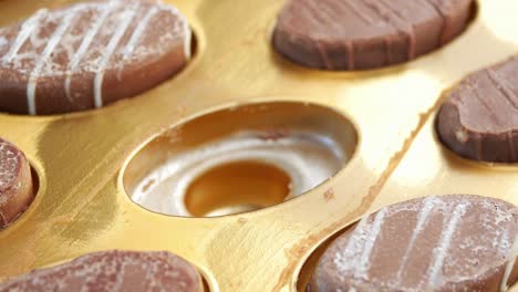 hand placing chocolate treat in a gold box