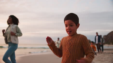 family, children and a boy running on the beach