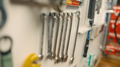 Close-up-on-wrenches-hanging-on-the-wall,-male-hand-choosing-size