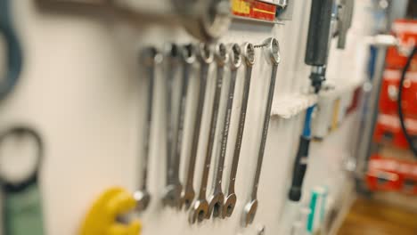 close up on wrenches hanging on the wall, male hand choosing size