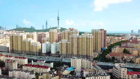 Aerial-View---Slow-pull-up-shot-with-a-view-over-Qingdao-City-in-Shandong-Province,-China-on-a-sunny,-clear-day