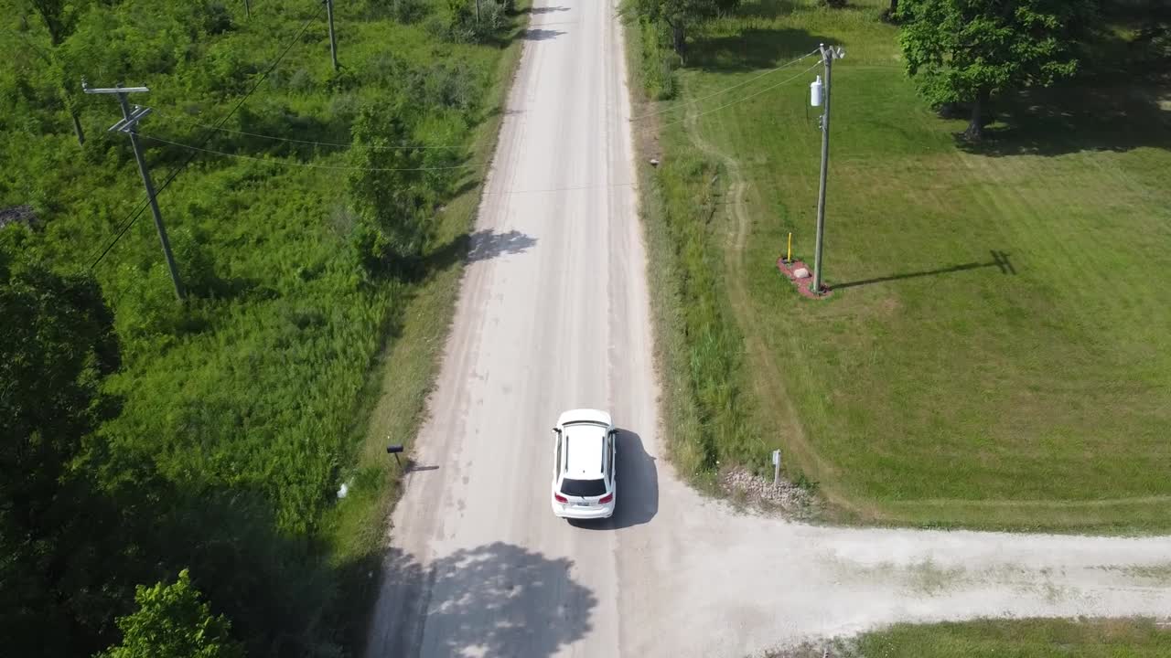 Un SUV bianco percorre un sentiero sterrato polveroso nel Michigan rurale