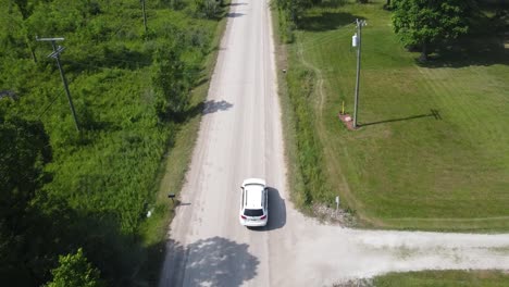 a white suv drives down a dusty gravel path in rural michigan