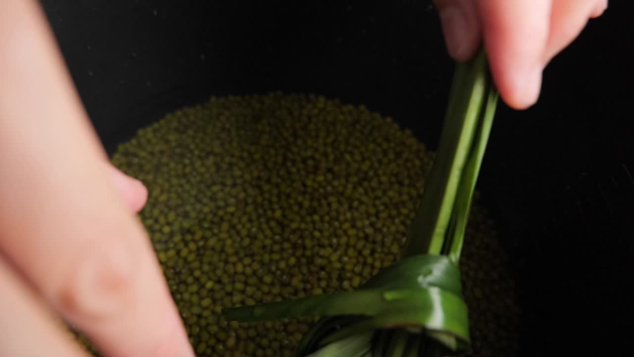 녹색 콩 죽 또는 bubur kacang hijau 요리를 위해 판단 잎을 냄비에 넣습니다.