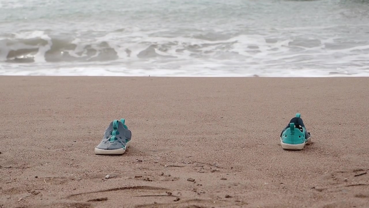 Et par børnesko efterladt på en sandstrand