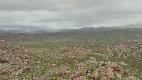 drone flies quickly past rock formation in desert landscape cederberg wilderness area in south africa - mountains in clouds can be seen in the background