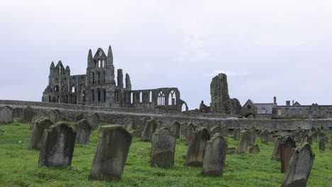 slow panning shot of the famous whitby abbey ruins with a cemetery in yorkshire