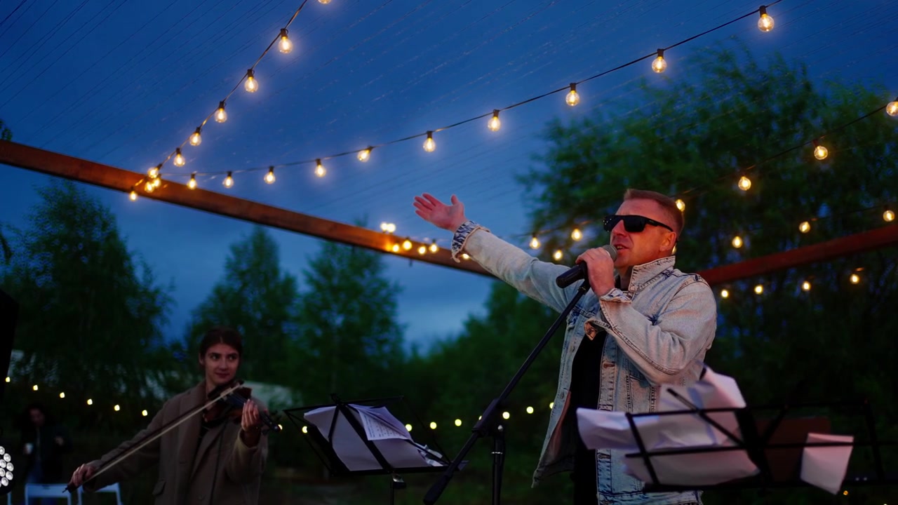 Male Singer and Violinist Performing Live Music Outdoors at Twilight