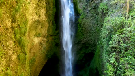 Carro-Fuera-De-La-Cascada-Brumosa-Escondida-Escondida-Entre-Paredes-Cubiertas-De-Vegetación,-Camión-A-La-Izquierda-Que-Conduce-A-Bosques-Densos