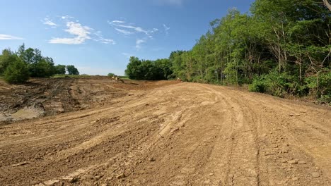 single bulldozer works to build side walls of a large pond at a new development site