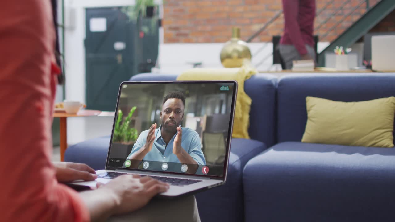mujer de negocios biracial que usa una computadora portátil para una videollamada con un colega de negocios afroamericano
