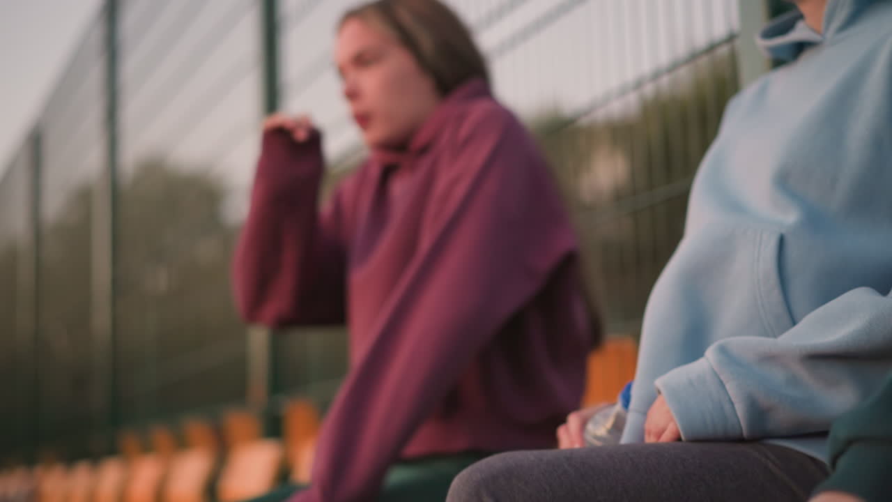 крупный план дам, расслабляющихся после долгой тренировочной сессии. одна женщина в зеленом спускает голову вниз, в то время как женщина в коричневом вытирает пот