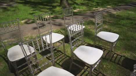 white glass chairs at a wedding ceremony in the park