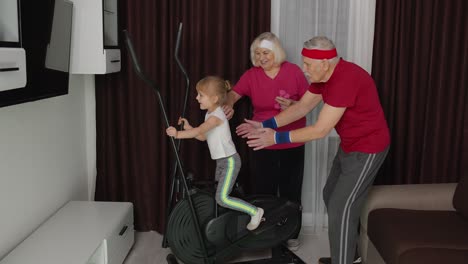 Active-old-senior-grandfather,-grandmother-training-kid-granddaughter-how-to-using-orbitrek-at-home