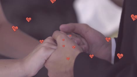Animation-of-hearts-over-hands-of-newly-married-caucasian-couple