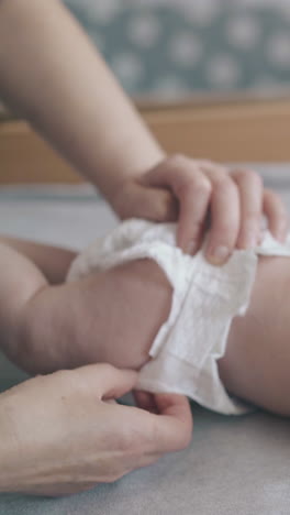 newborn boy with short fair hair and in white diaper lies on stomach on changing table and enjoys massage closeup