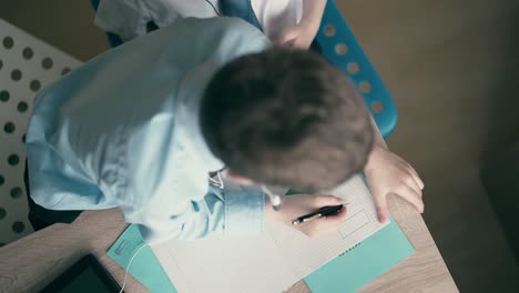 High-angle-shot-Children-do-school-homework-the-elder-brother-in-headphones-1