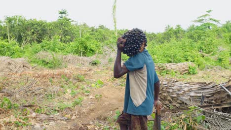 young black male farmer carrying on his shoulder young coconut in slow motion crossing a field farm in africa