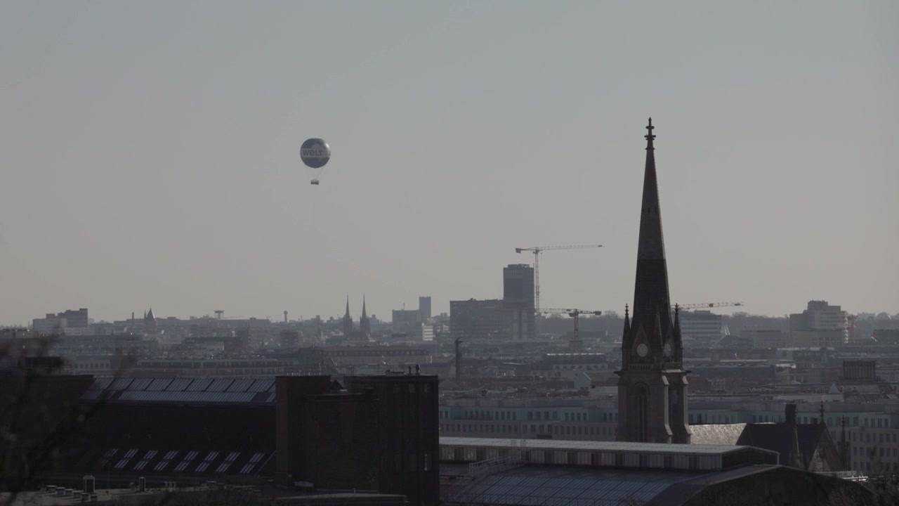 Skyline von Berlin, Deutschland, mit dem WELT Heißluftballon am Himmel an einem bewölkten und sonnigen Tag.