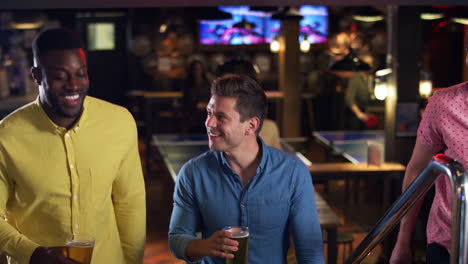 tres amigos masculinos subiendo las escaleras mientras se reúnen para tomar bebidas y socializar en el bar