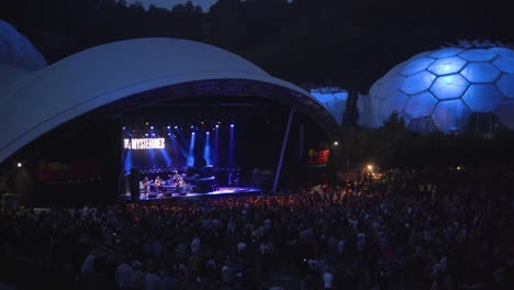 band performing on stage infront of their fans at the eden project biome domes in cornwall uk. - wide