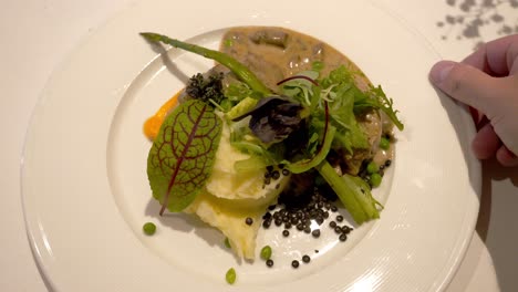 lunch dish on a plate, mashed potatoes, pork tenderloin in its own sauce with pickled pepper