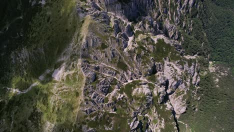 Aerial-shot-over-the-rugged-cliffs-of-Piatra-Craiului-Mountains,-lush-greenery-below