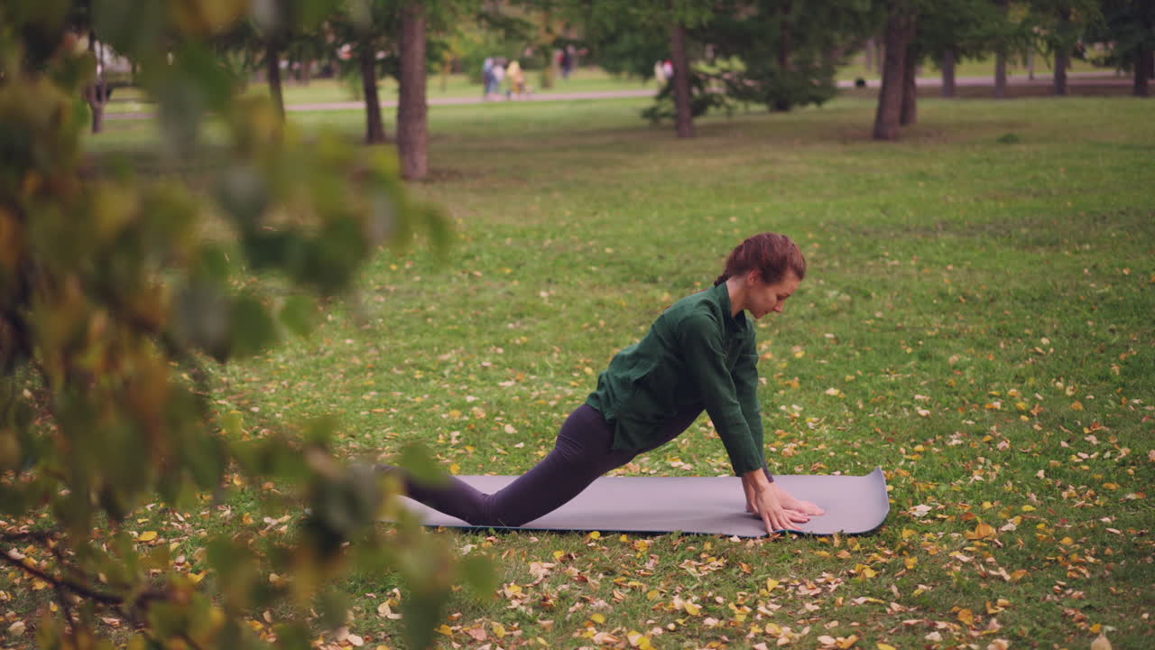 Woman practicing yoga in a park during autumn