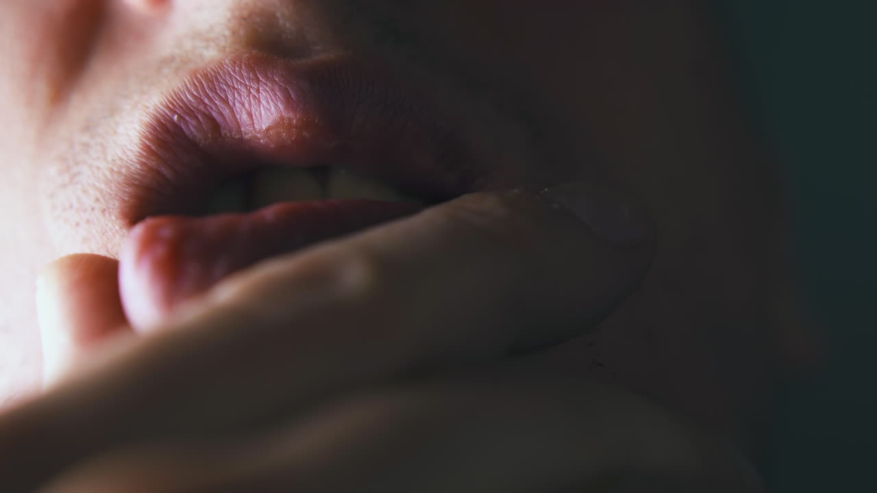 мужчина держит ладонь на подбородке под губой и двигает открытым ртом