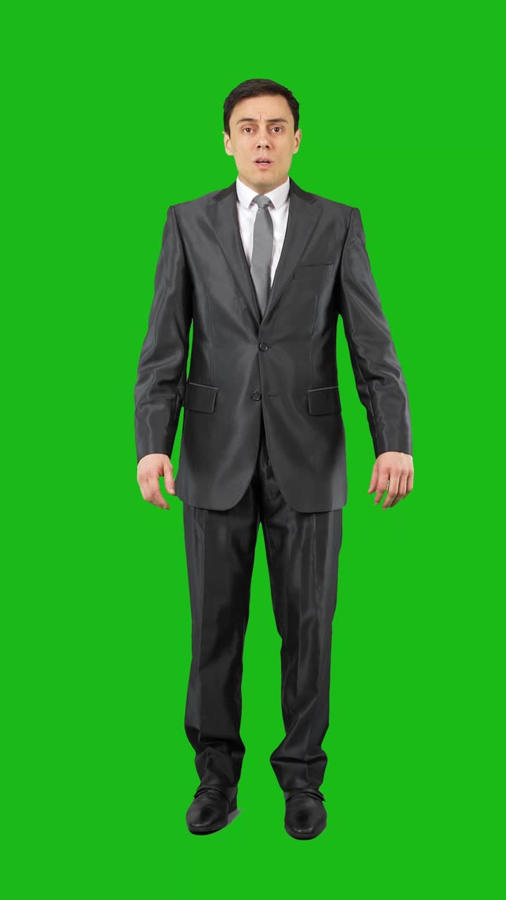 Man in suit looking scared and holding hands up on green screen