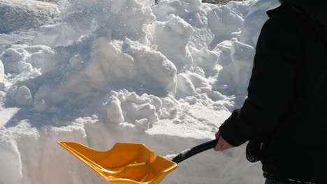 close up of man shoveling snow off a trench