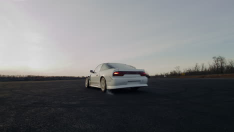 white car drifting on a track at sunset