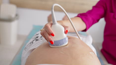 ultrasound scan to a pregnant woman in hospital. gynecologist using transducer on female's belly during sonography procedure.