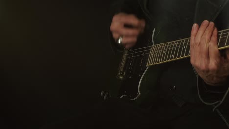male musician on dark hazy stage plays electric guitar, copy space