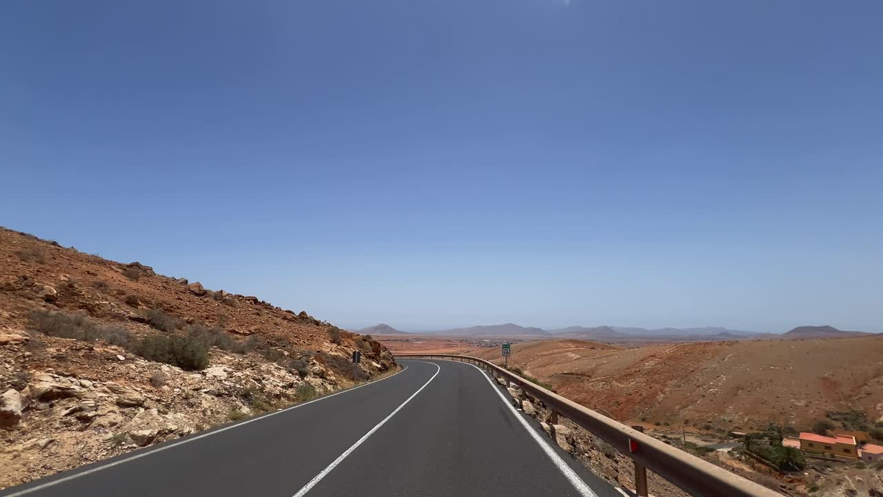 POV driving shot on a winding road through the arid, mountainous landscape near Betancuria, Fuerteventura. For road trip and travel concepts. Canary Islands, Spain