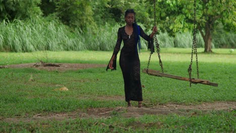 black woman in black dress on a swing in a park