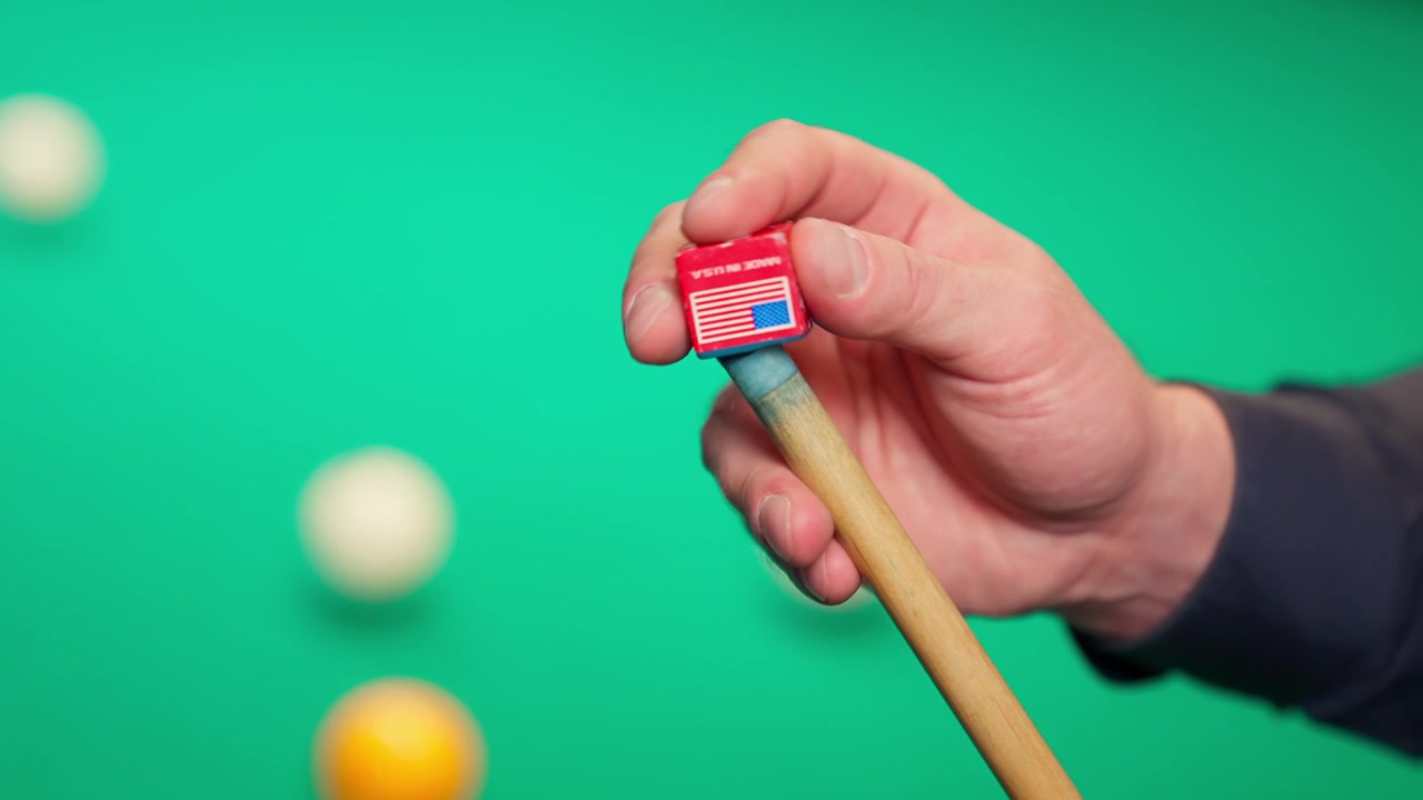 Close-Up of Hand Chalking a Pool Cue on a Green Billiards Table
