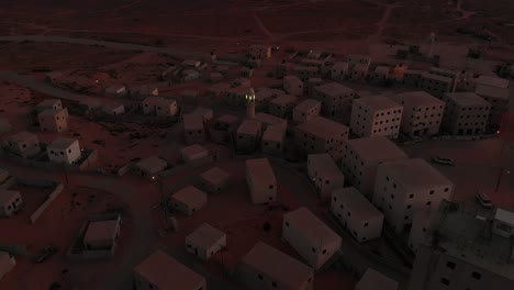 aerial view at morning of an empty arabic city near gaza in palestine with mosque with green shining lights in the middle.
