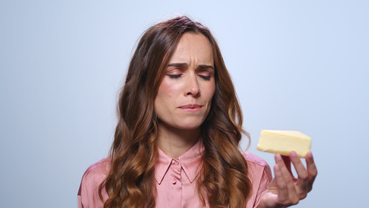 mujer de negocios molesta mirando pastel en la mano. mujer oliendo pastel de queso