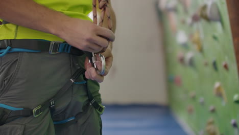 Portrait-of-a-climber-preparing-to-climb-the-wall-in-the-hall-to-chalk-his-hands-and-climb-the-wall-with-insurance-in-slow-motion.