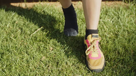 medium shot of woman lacing up sneakers in summer park